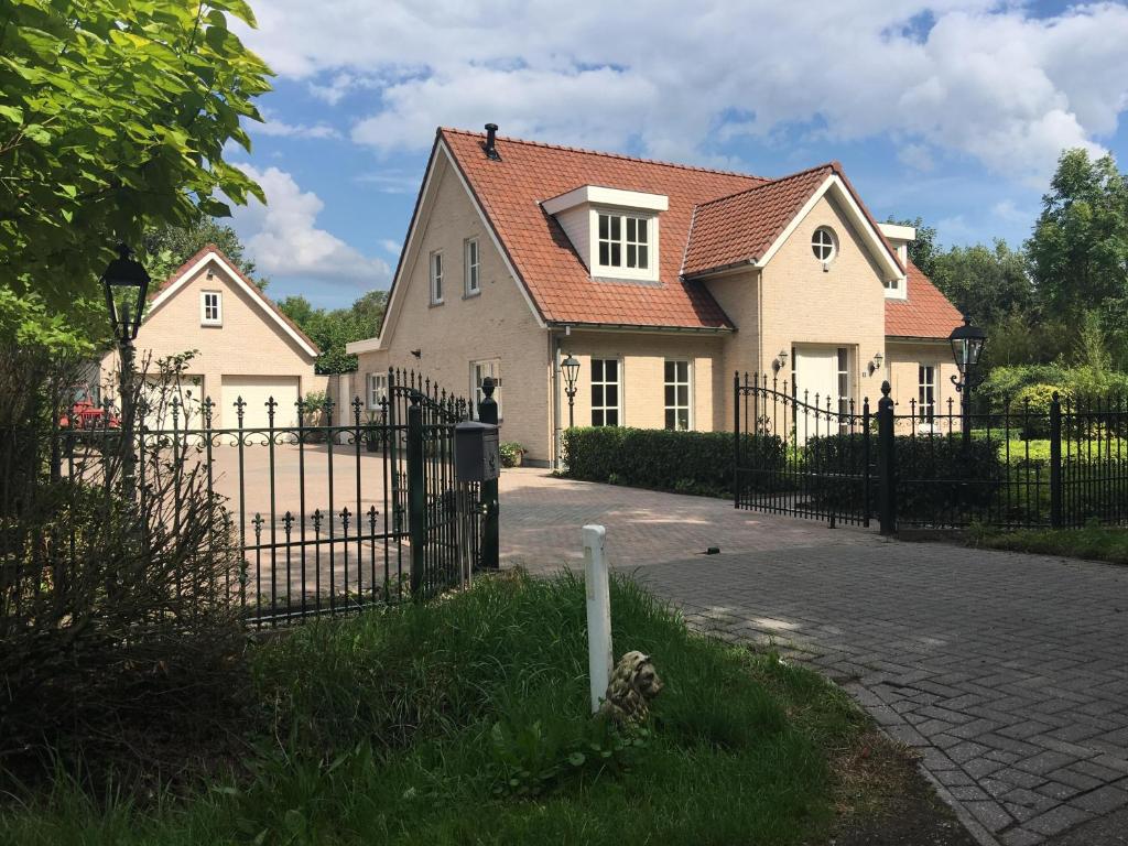 a house with a black fence and a driveway at Koekwhouse Bed and Breakfast, Bierbrouwerij in Nispen