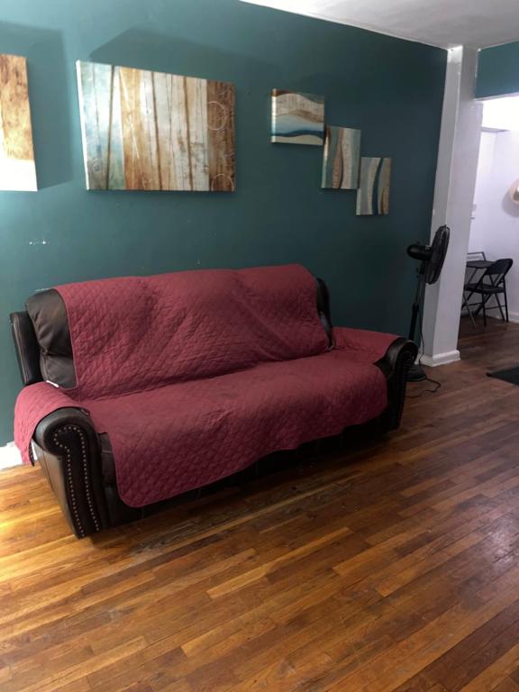 Sofá rojo en una habitación con suelo de madera en Comfy apartment en Hollis