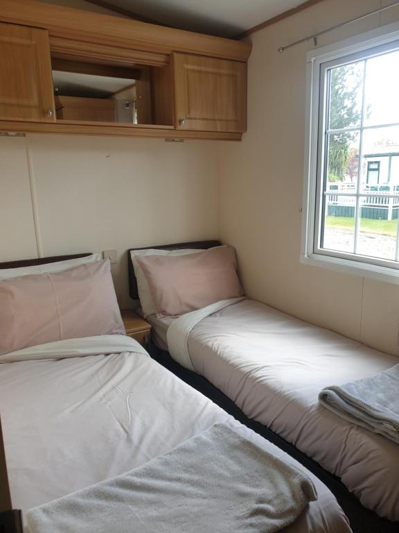 two beds in a small room with a window at Sunrise Holidays Skegness - Diamond in Skegness