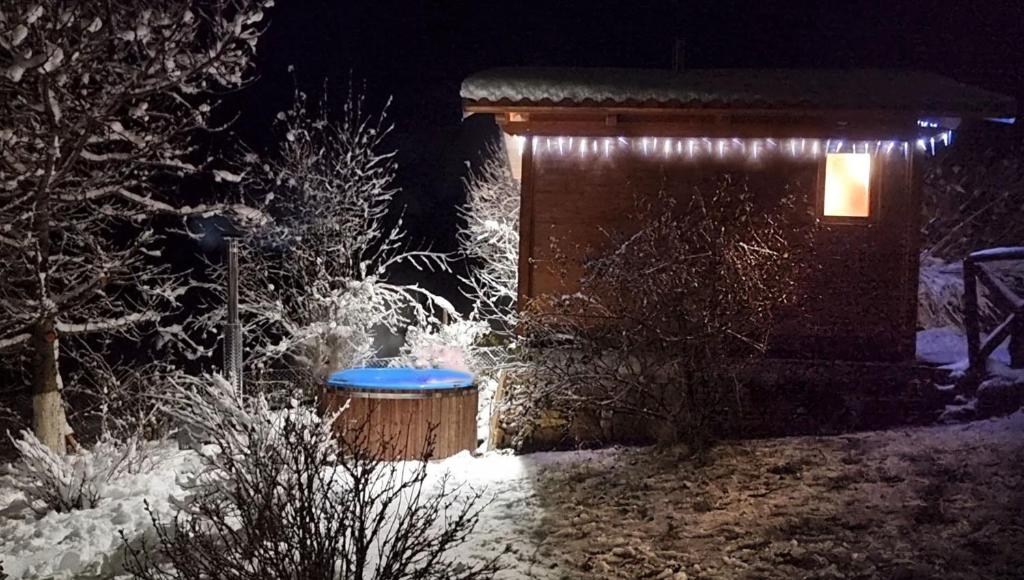 ロリカにあるCasale dell'Arvoの夜の雪の中に青いベンチが付いたキャビン