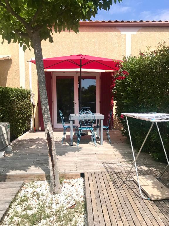 - une table et des chaises sous un parasol rouge sur la terrasse dans l'établissement Maison, à Béziers