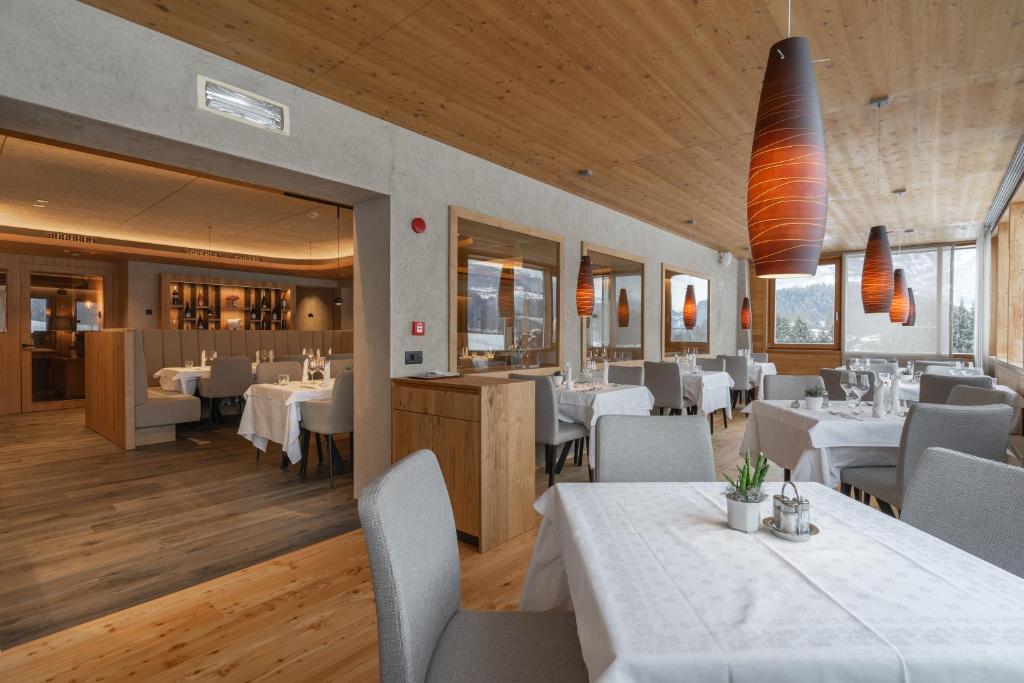 jadalnia z białymi stołami i białymi krzesłami w obiekcie Hotel Krondlhof w mieście Brunico