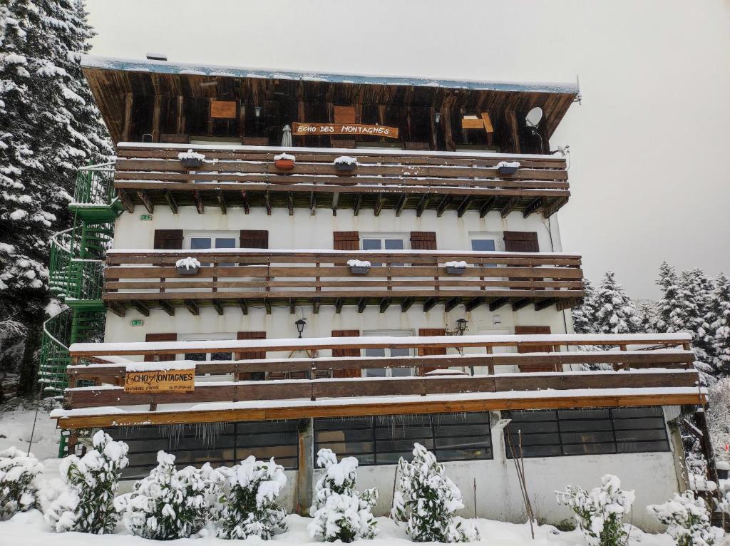 un grand bâtiment avec de la neige au sol dans l'établissement Echo des montagnes, à Chalmazel Jeansagniere