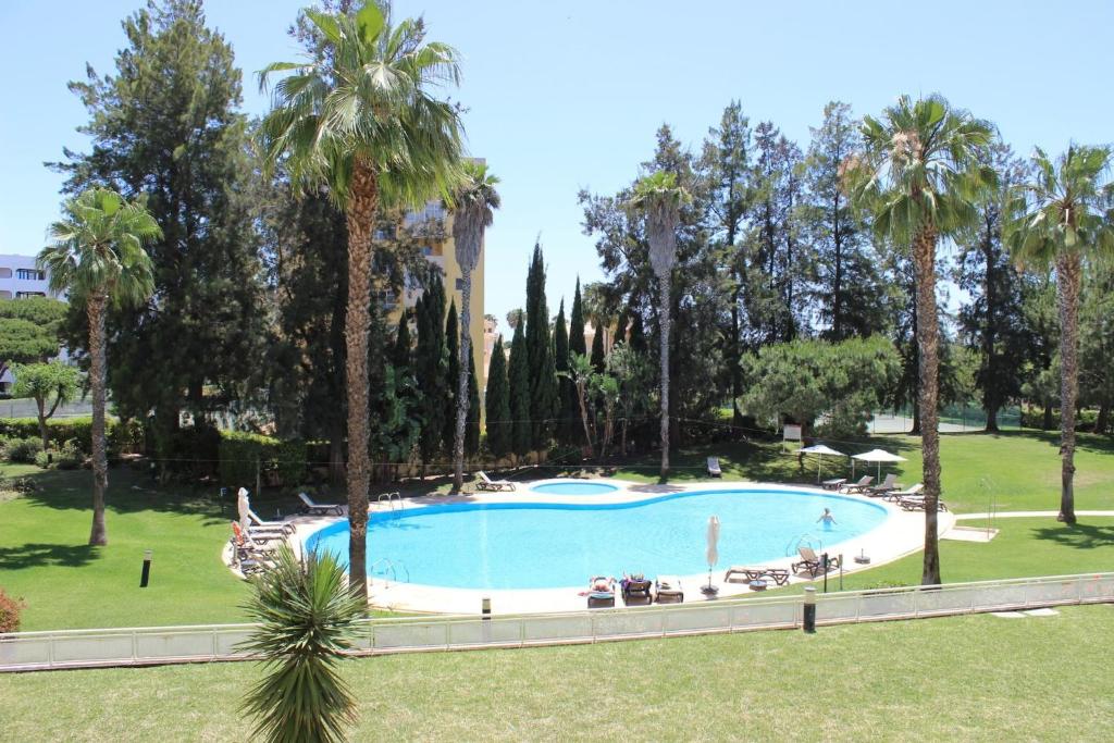 a large swimming pool in a park with palm trees at Da Praia Apartment - Pool & Tenis in Vilamoura