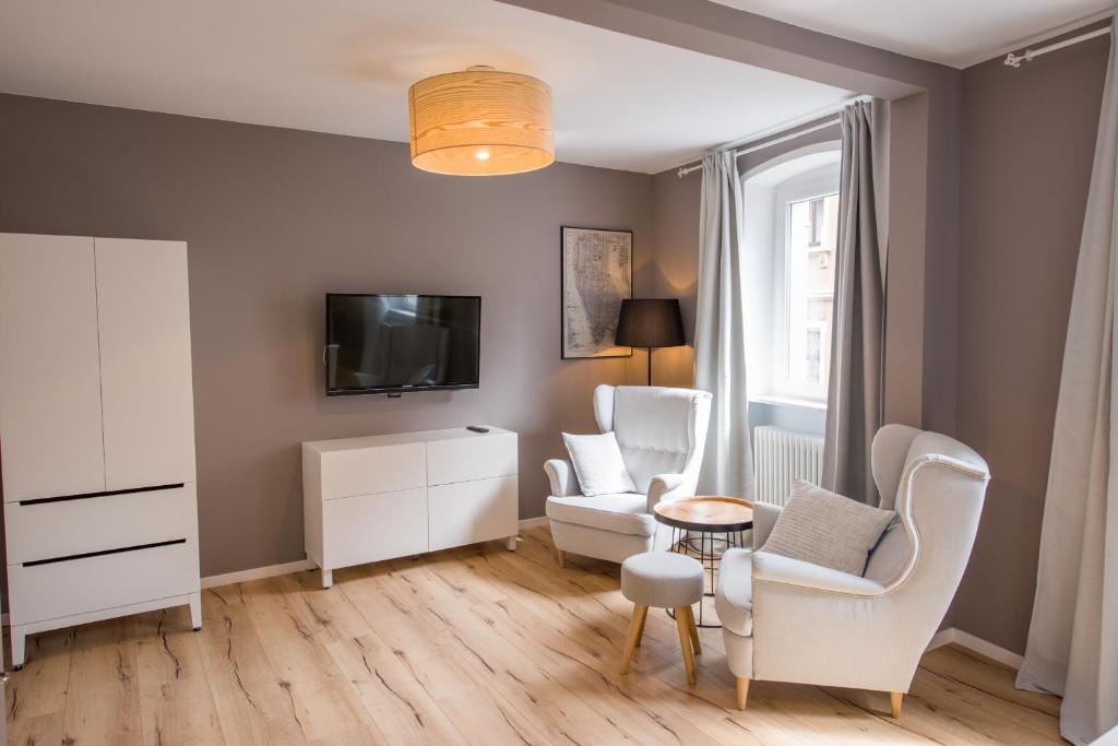 ein Wohnzimmer mit weißen Stühlen und einem TV in der Unterkunft Brombeerhaisel in Sankt Martin