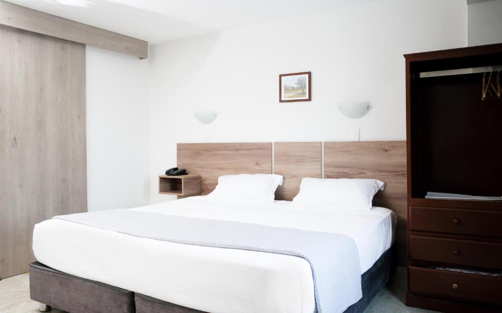 a bedroom with a large white bed with a wooden headboard at Hotel Santa Rosa in Chiclayo
