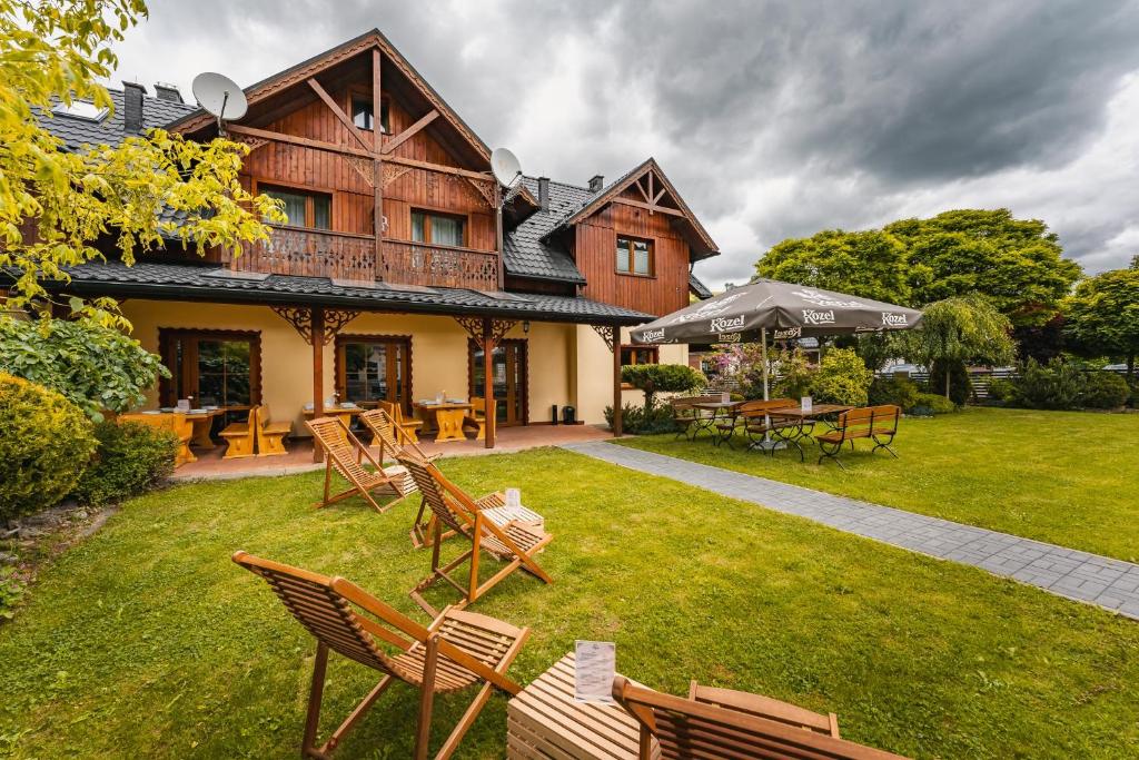 une maison avec des chaises et des tables dans une cour dans l'établissement Osada turystyczna Malinów, à Szczawnica