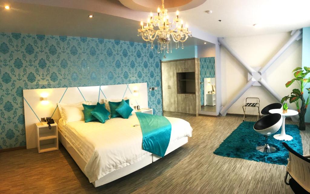 Un dormitorio con una cama con paredes azules y una lámpara de araña. en Luma Plaza Hotel, en Pereira