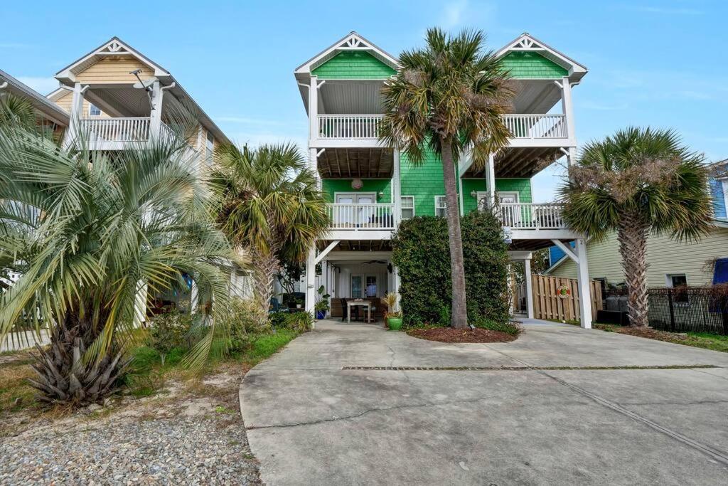 une maison verte avec des palmiers devant elle dans l'établissement Blue Ocean Bungalow, à Carolina Beach