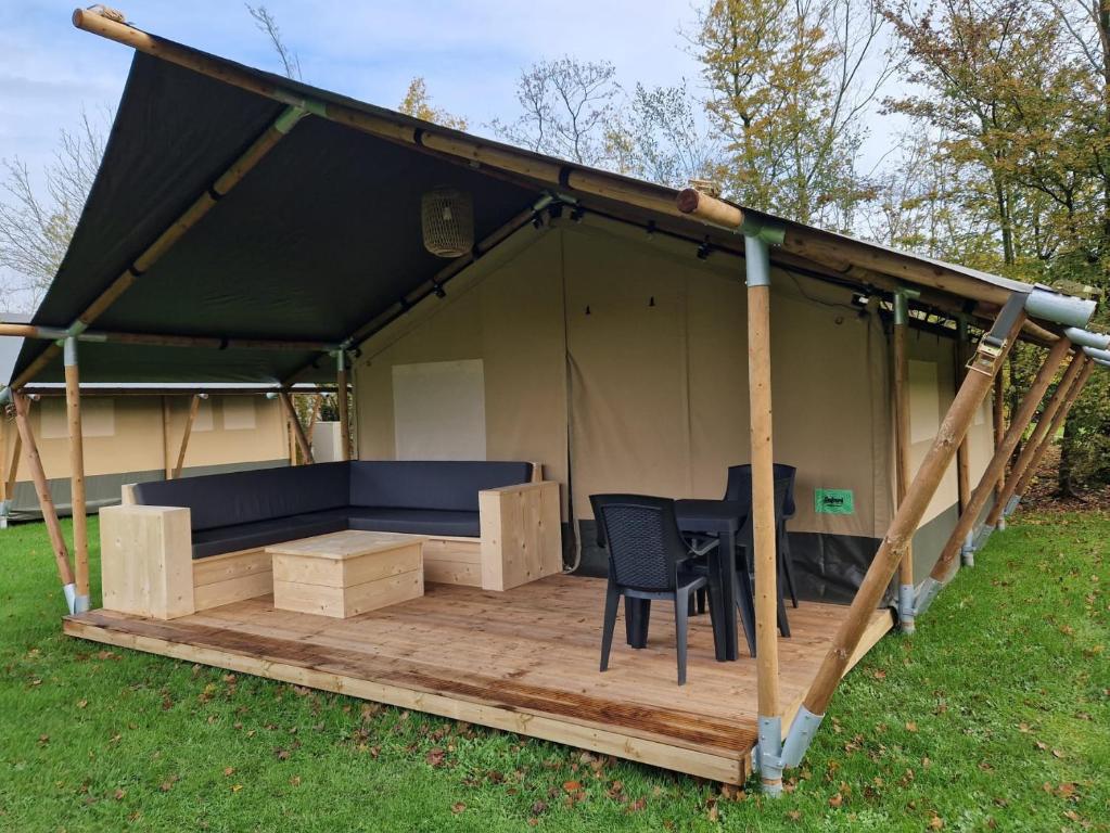 a tent with a table and chairs on a deck at Safaritent Alkenhaer Appelscha in Appelscha