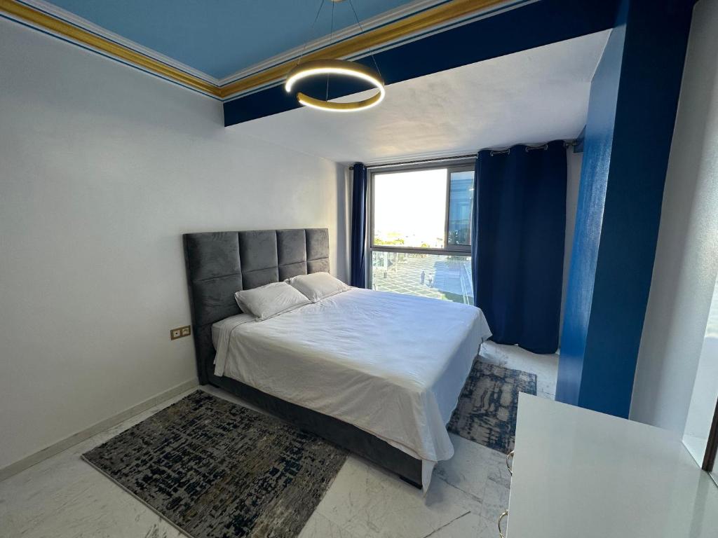 a bedroom with a bed and a large window at LOCATION HICHAM in Tangier