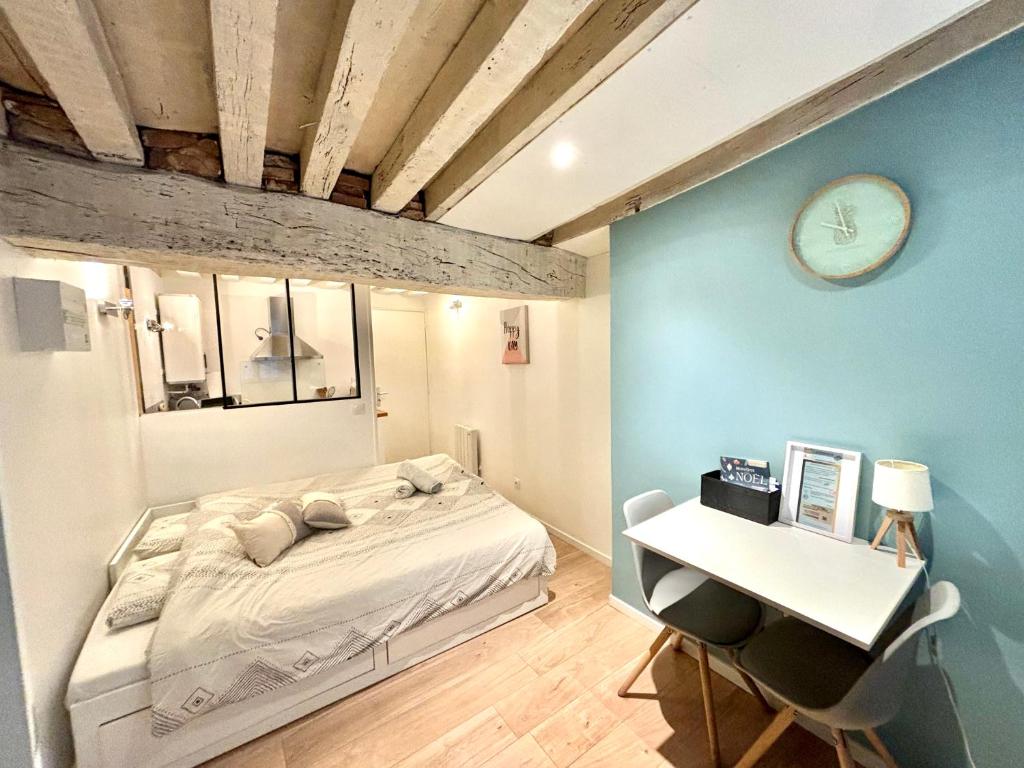 a bedroom with a bed and a desk and a clock at Studio dans Quartier historique de MOULINS in Moulins