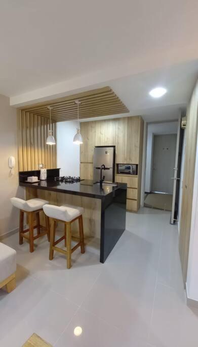 a kitchen with a black counter and chairs in it at Se alquila apartamento in Cali