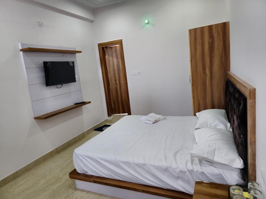 1 dormitorio con 1 cama y TV en la pared en Hotel Happy Home en Alīgarh