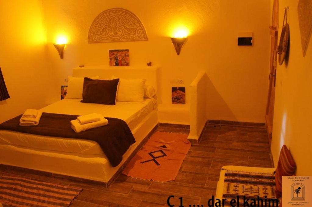 1 dormitorio con 1 cama blanca y 2 toallas en Dar El Hakim, le petit hôtel de Timimoun, en Timimoun