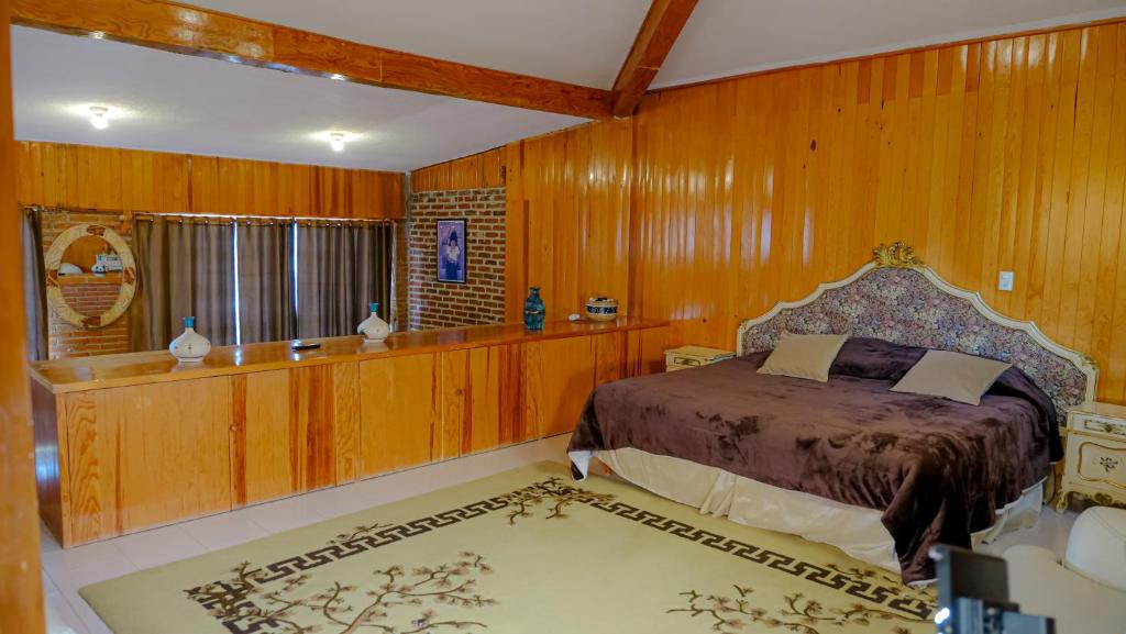 sypialnia z drewnianymi ścianami i łóżkiem w pokoju w obiekcie Cabañas- Casas España w mieście Mineral del Chico