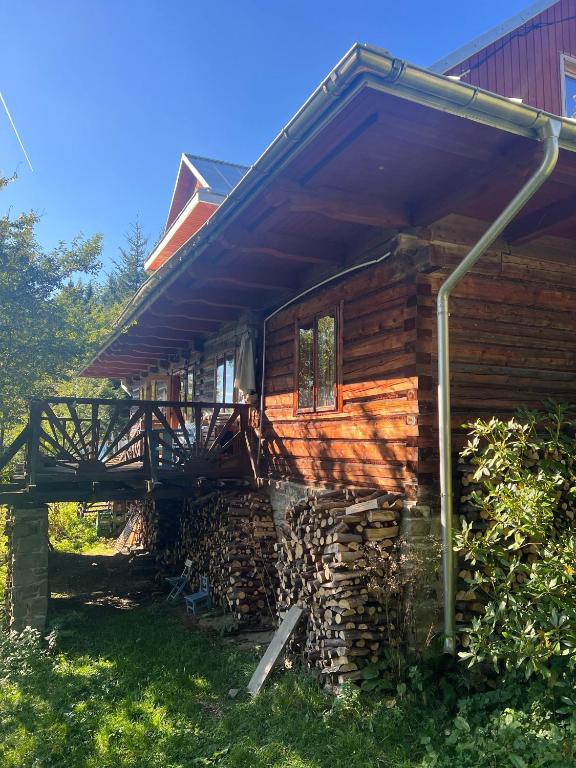 a log cabin with a deck and a pile of logs at Chałupa z widokiem w górach in Zawoja