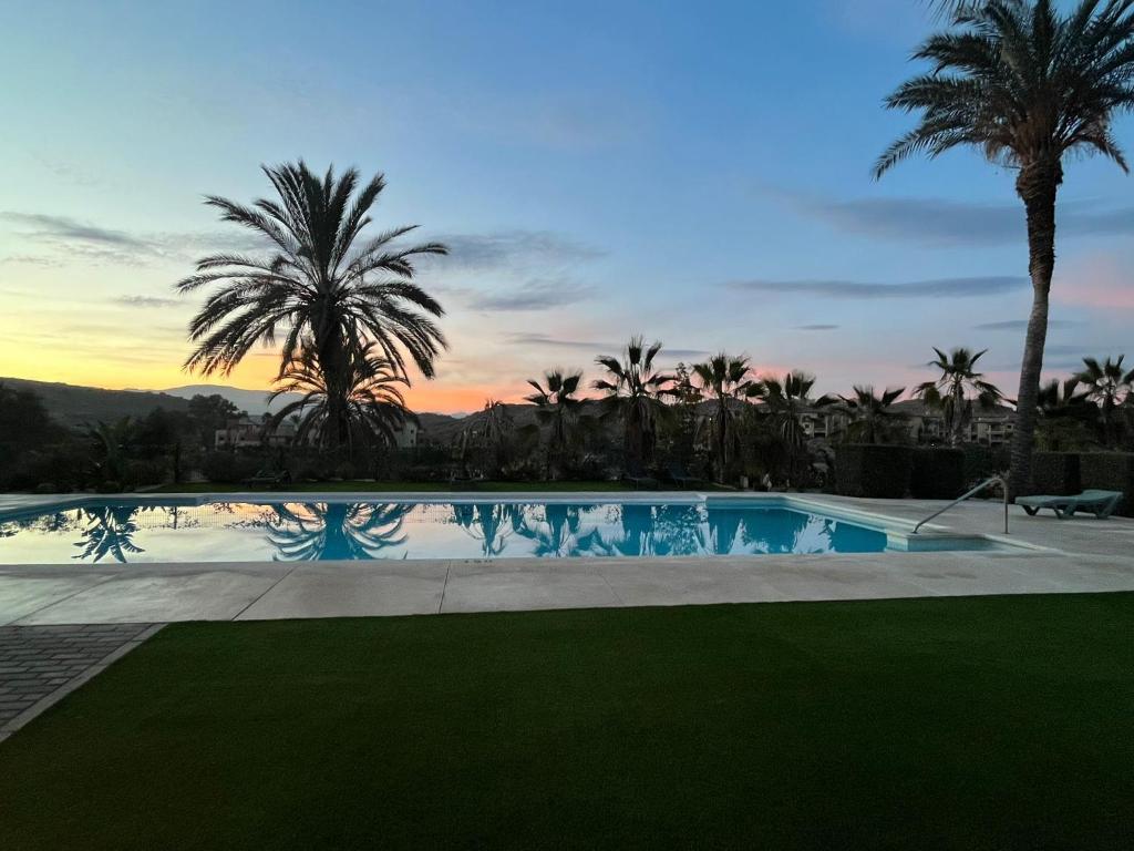 una piscina con palme e tramonto di Apartament Golf lujo, Perla Sol 2 a Vera