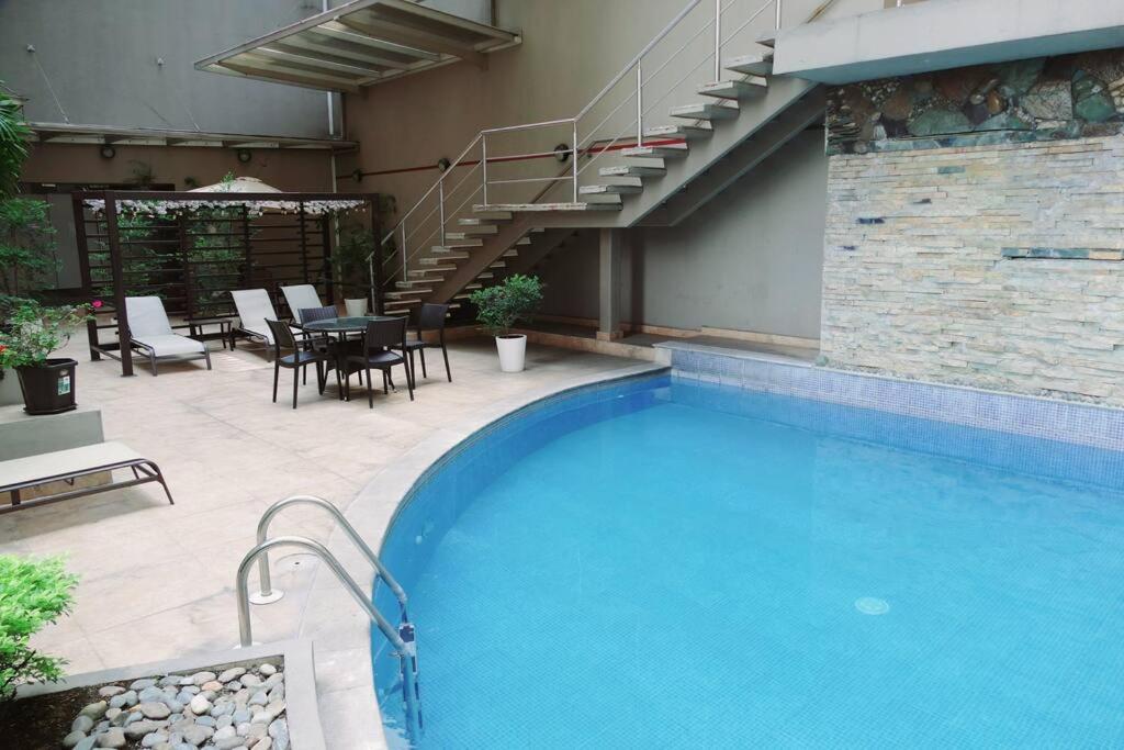 a swimming pool with a table and chairs next to a building at Ecusuites Penthouse Torre Sol Aeropuerto Mall Del Sol in Guayaquil