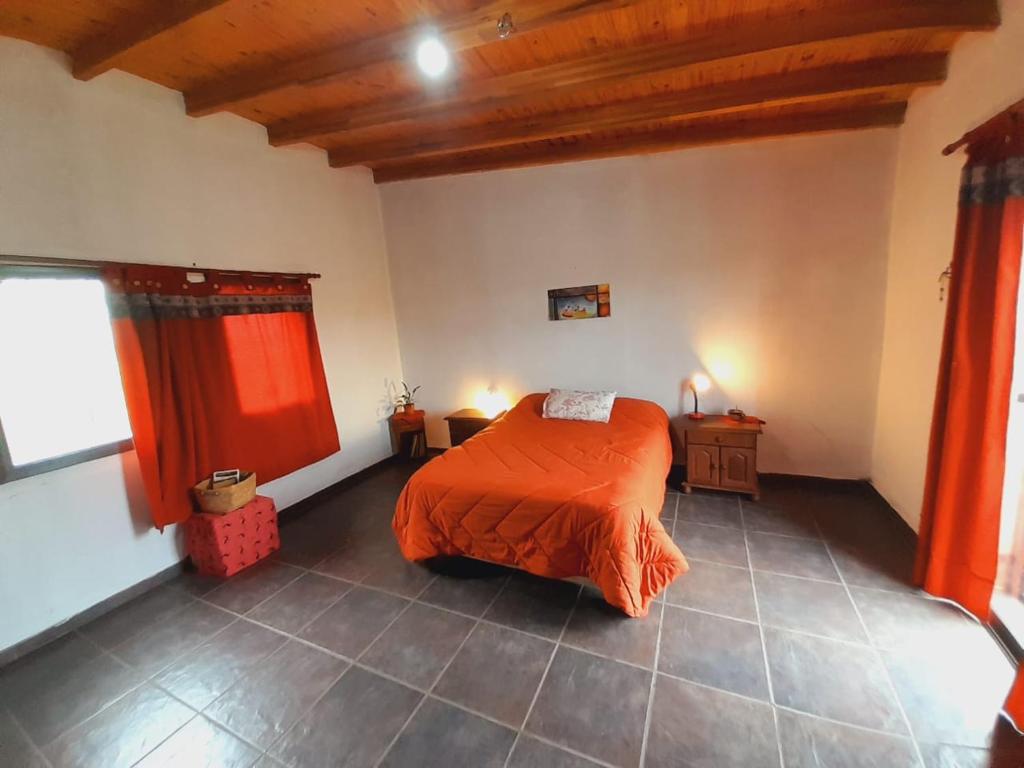 a bedroom with a bed with an orange comforter at Casa de la Montaña in Villa Parque Siquiman