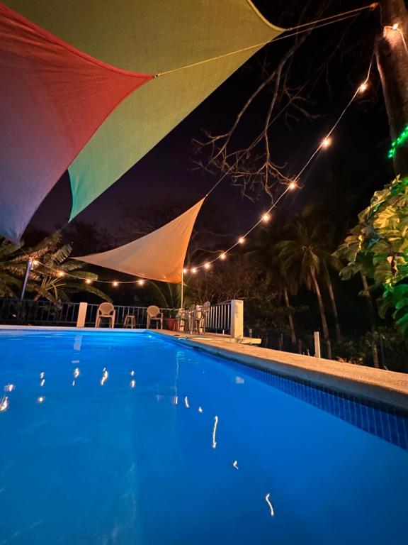 a swimming pool at night with a large umbrella at Stunning Beach/Cliff side studio in paradise in Tamanique
