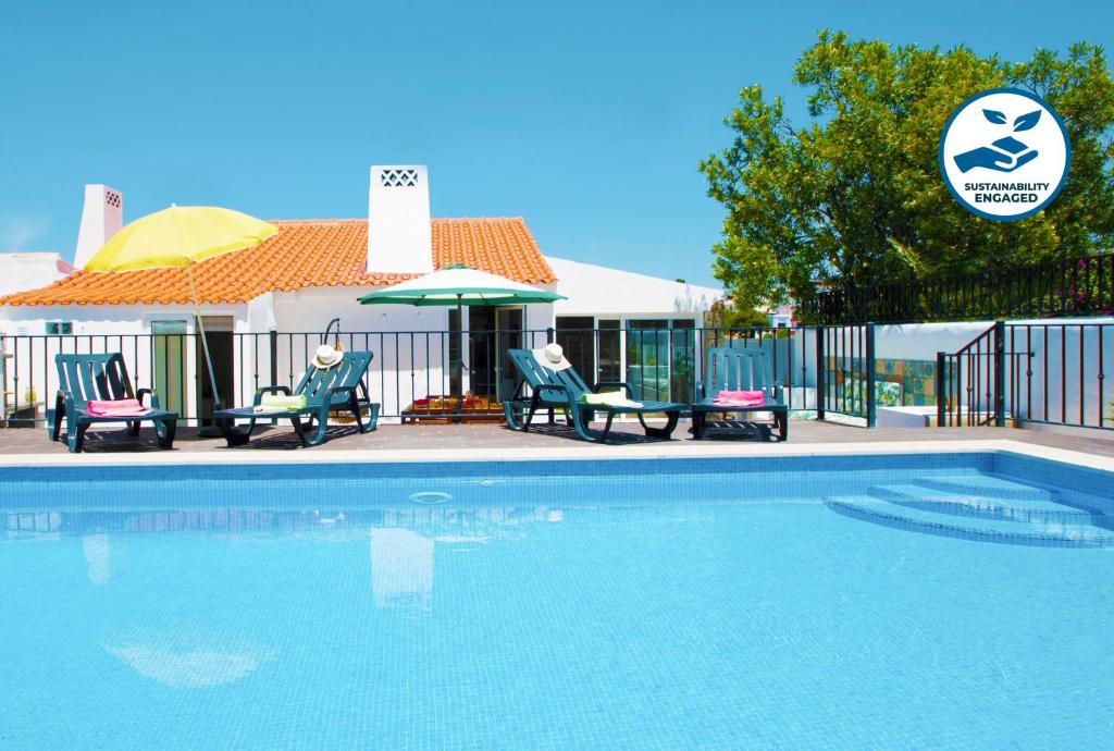 a swimming pool with two chairs and a table and umbrella at Villa São Paulo by Algarve Vacation in Albufeira