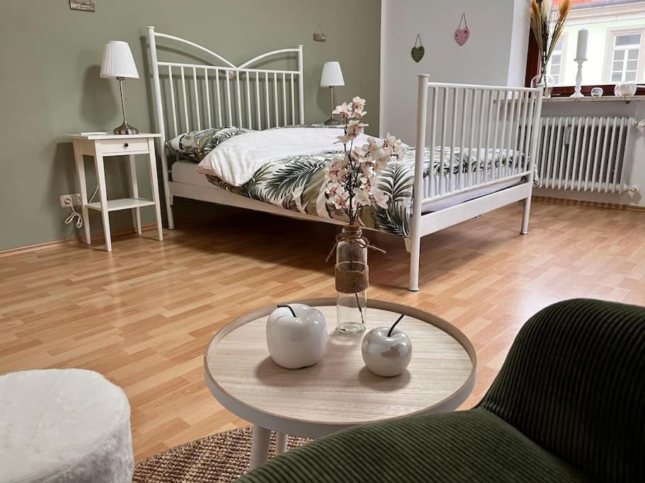 a living room with a bed and a table with flowers at Geräumige Idylle im Grünen bei Bamberg in Walsdorf