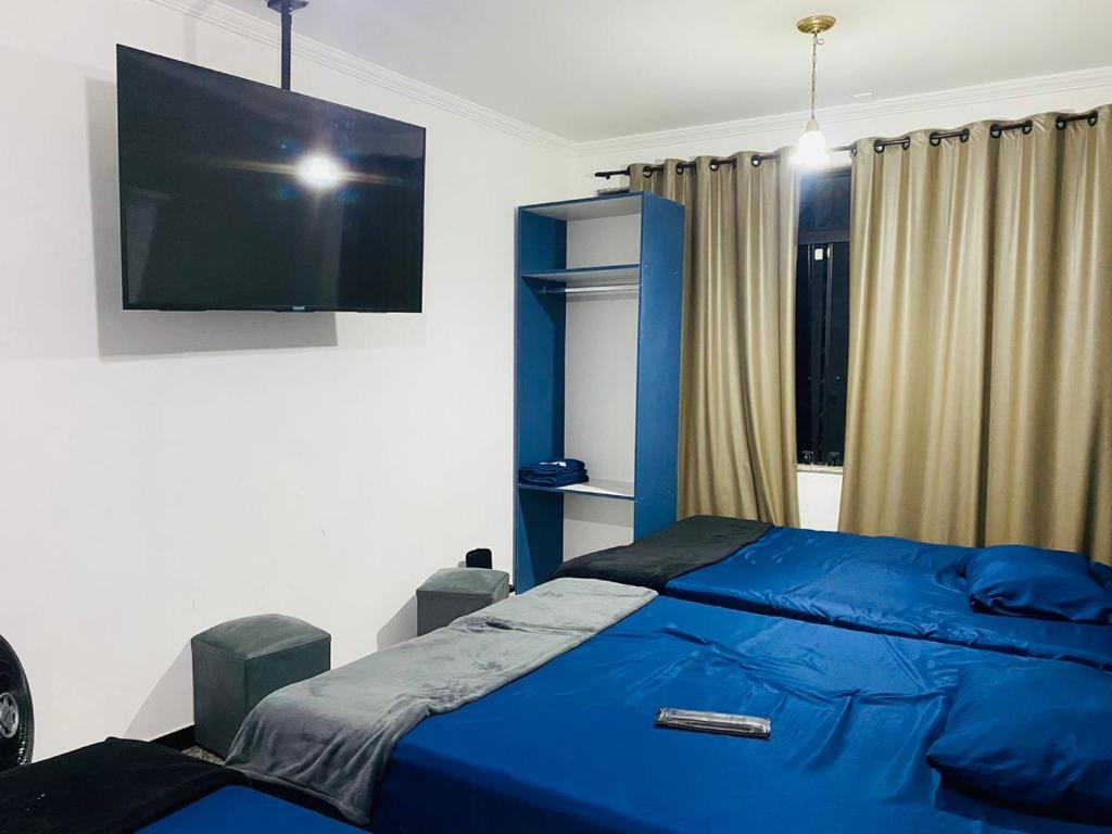a bedroom with a blue bed and a flat screen tv at HOSTEL ANPRADO in Guarulhos