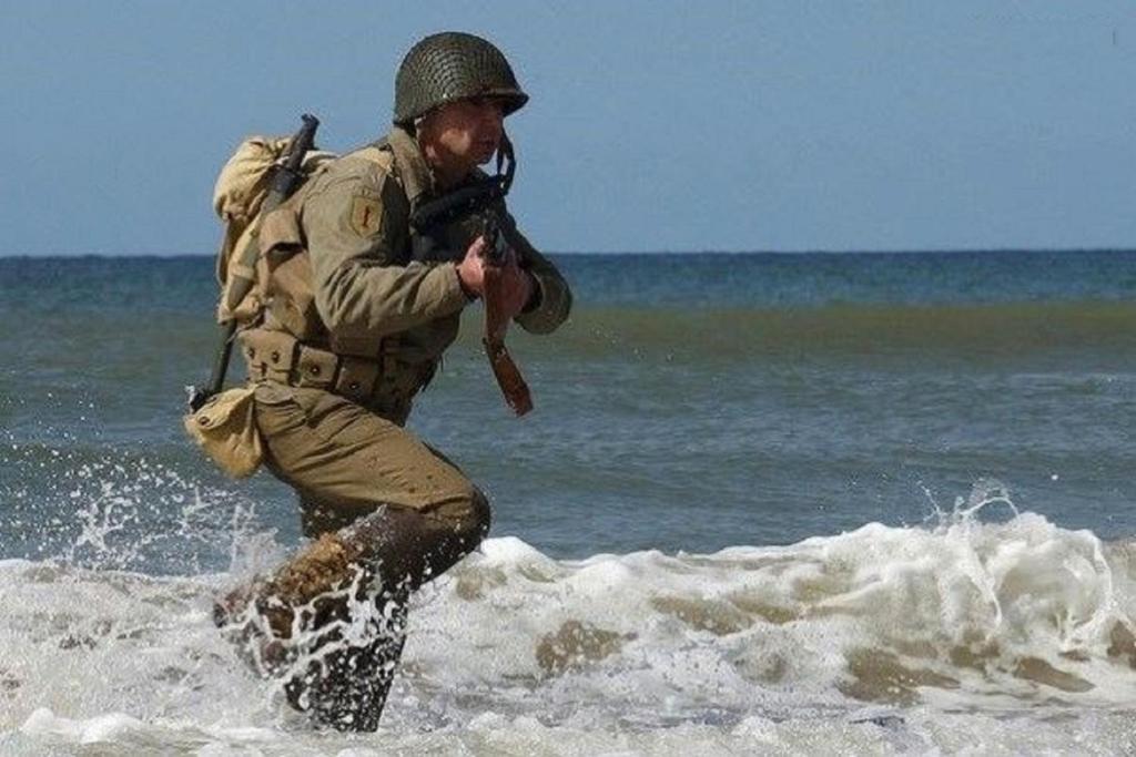 a man is walking in the water on the beach at Villa Victorine Omaha Beach in Saint-Laurent-sur-Mer