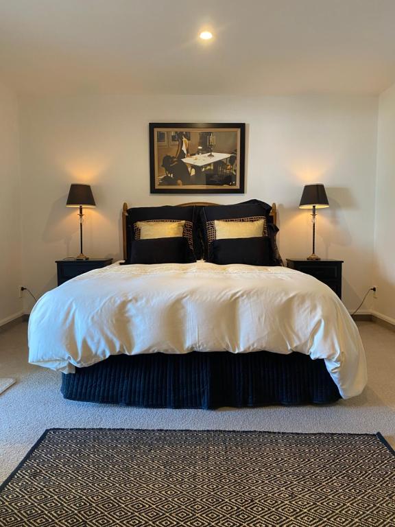 a bedroom with a large bed with two lamps at Maison Blue - Chic Garden Apartment in Napier