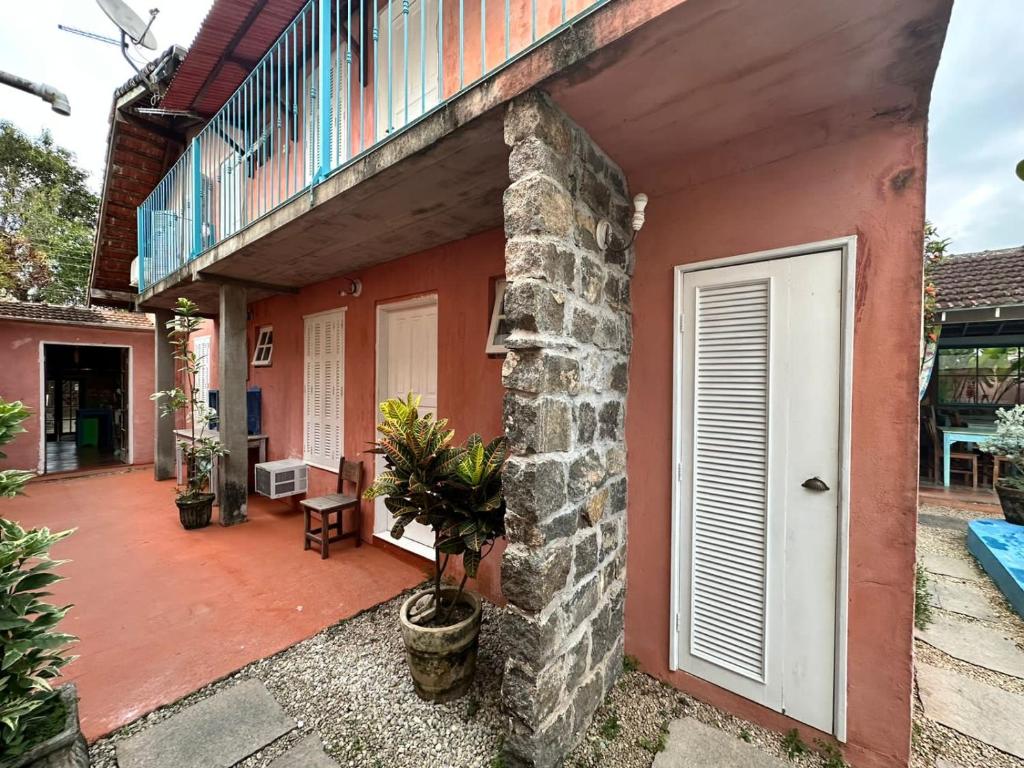 une maison rouge avec une porte blanche et une terrasse dans l'établissement Vila Luiza Ubatuba, à Ubatuba