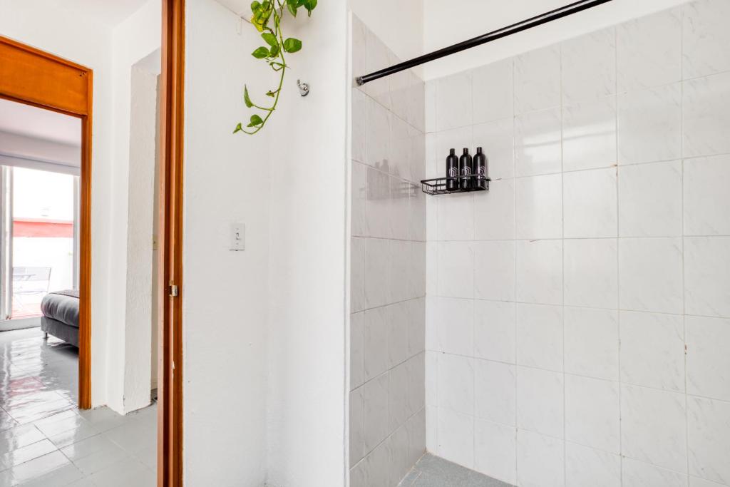 a bathroom with a shower with white tiles at Casa Lumo in Roma Norte by Tasman in Mexico City