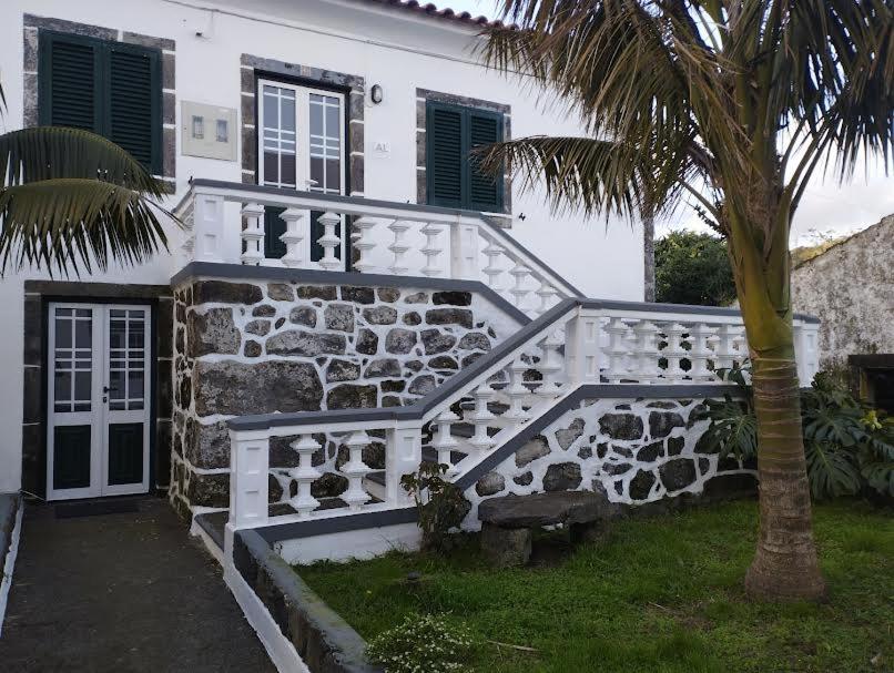 een wit huis met een trap en een palmboom bij Casa das Palmeiras in Lajes das Flores