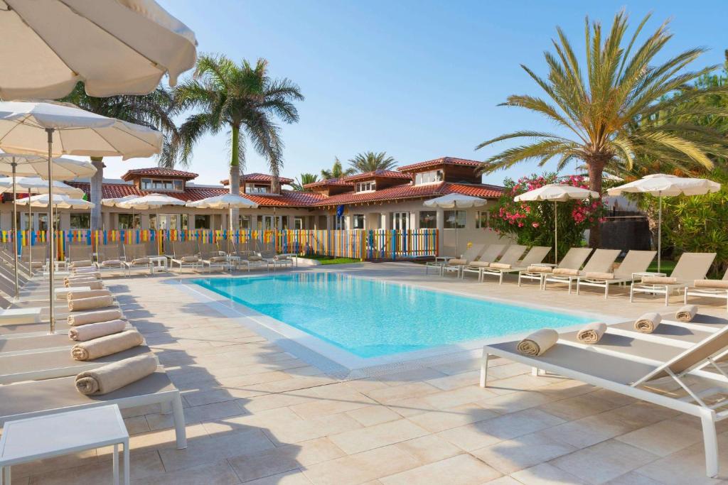 a swimming pool with lounge chairs and umbrellas at Alua Suites Fuerteventura - All Inclusive in Corralejo