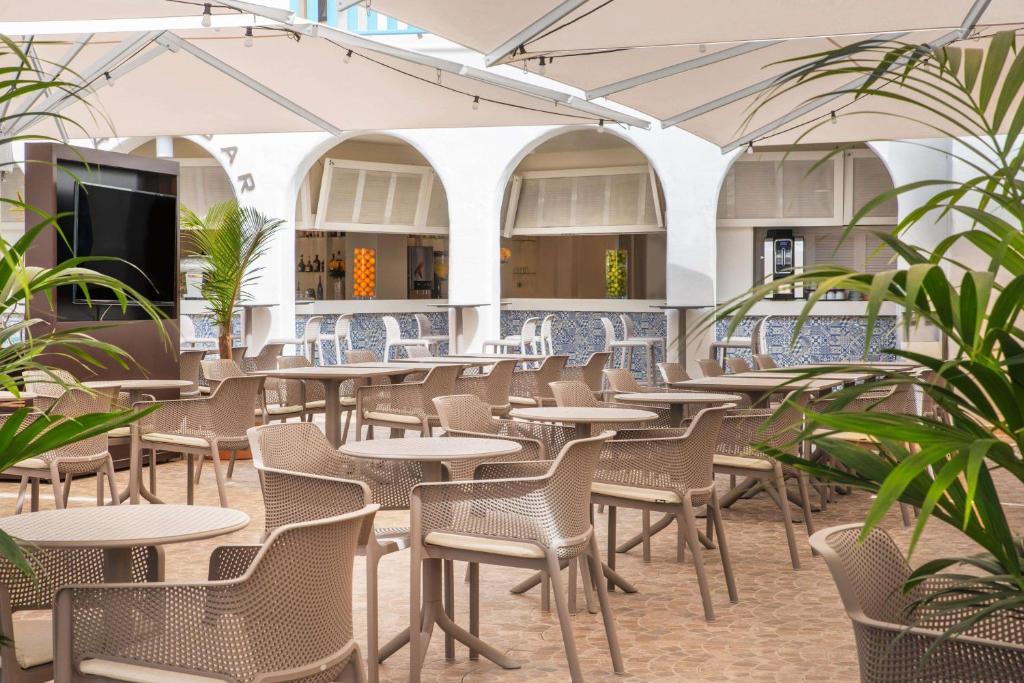 an empty restaurant with tables and chairs and plants at Alua Suites Fuerteventura - All Inclusive in Corralejo