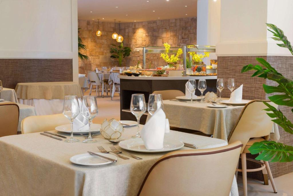 a dining room with tables and chairs with glasses at Alua Suites Fuerteventura - All Inclusive in Corralejo