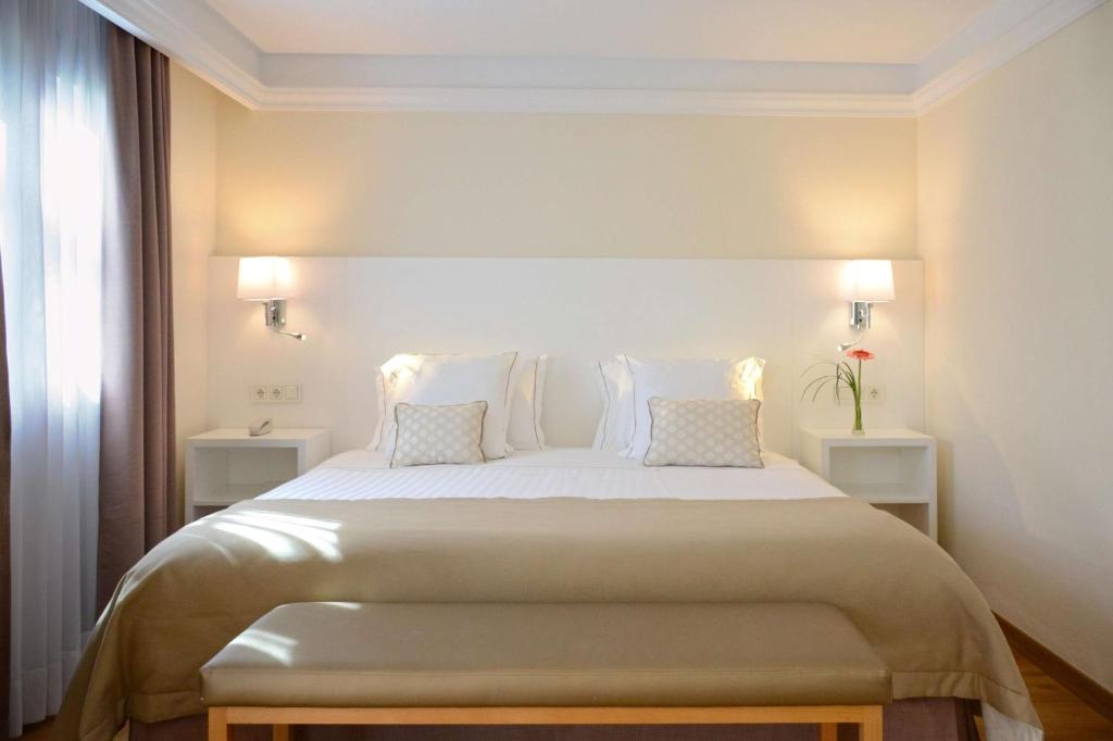 a bedroom with a large white bed with two night stands at Alua Suites Fuerteventura - All Inclusive in Corralejo