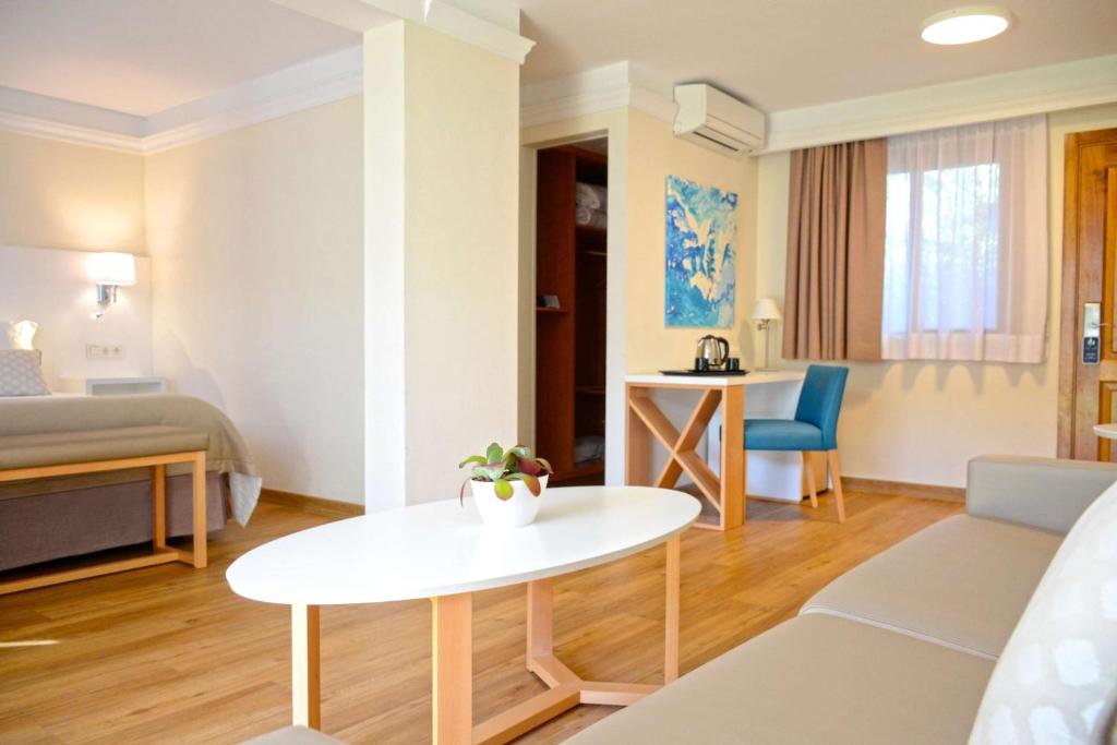 a living room with a bed and a table in a room at Alua Suites Fuerteventura - All Inclusive in Corralejo