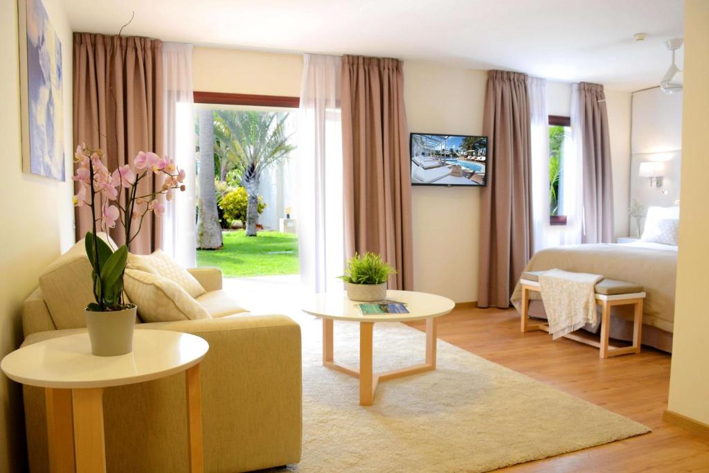 a living room with a couch and a bed and a table at Alua Suites Fuerteventura - All Inclusive in Corralejo