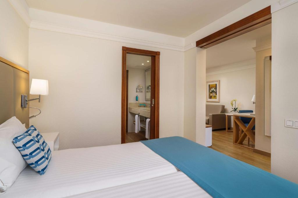 a hotel room with a bed and a bathroom at Alua Suites Fuerteventura - All Inclusive in Corralejo