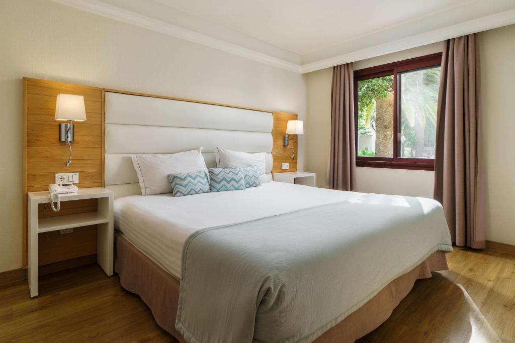 a hotel room with a large bed and a window at Alua Suites Fuerteventura - All Inclusive in Corralejo