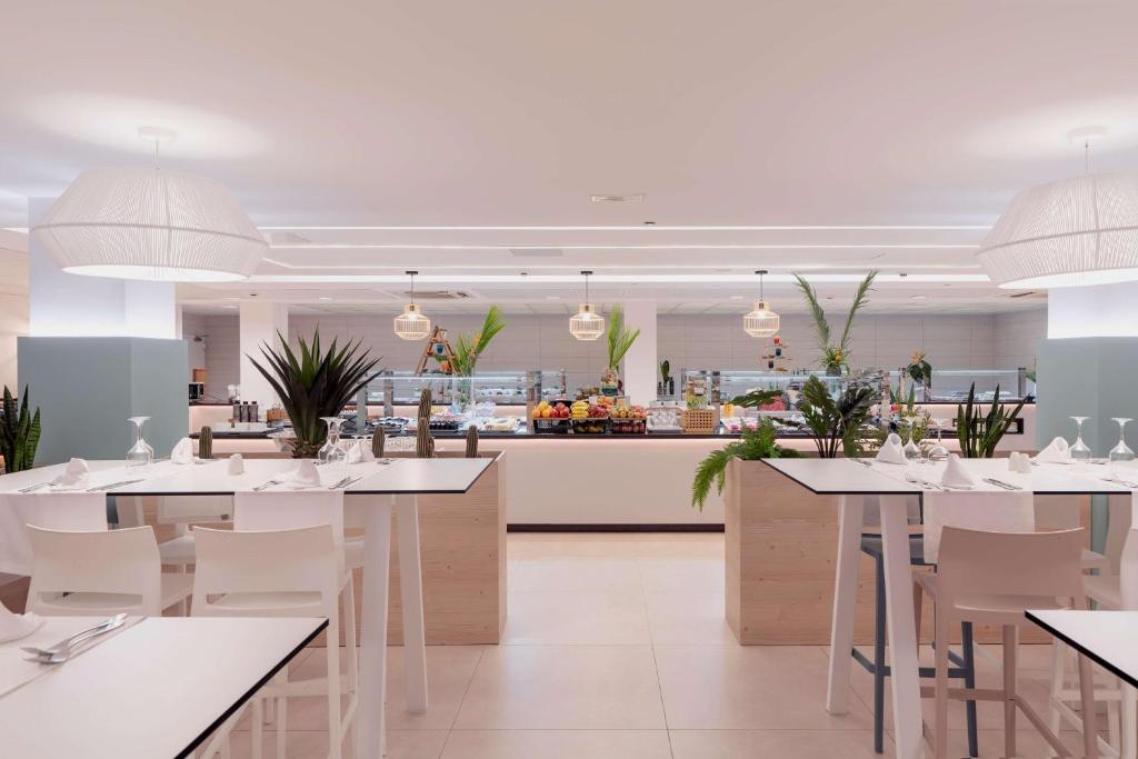 a restaurant with white tables and chairs and a counter at Alua Suites Fuerteventura - All Inclusive in Corralejo