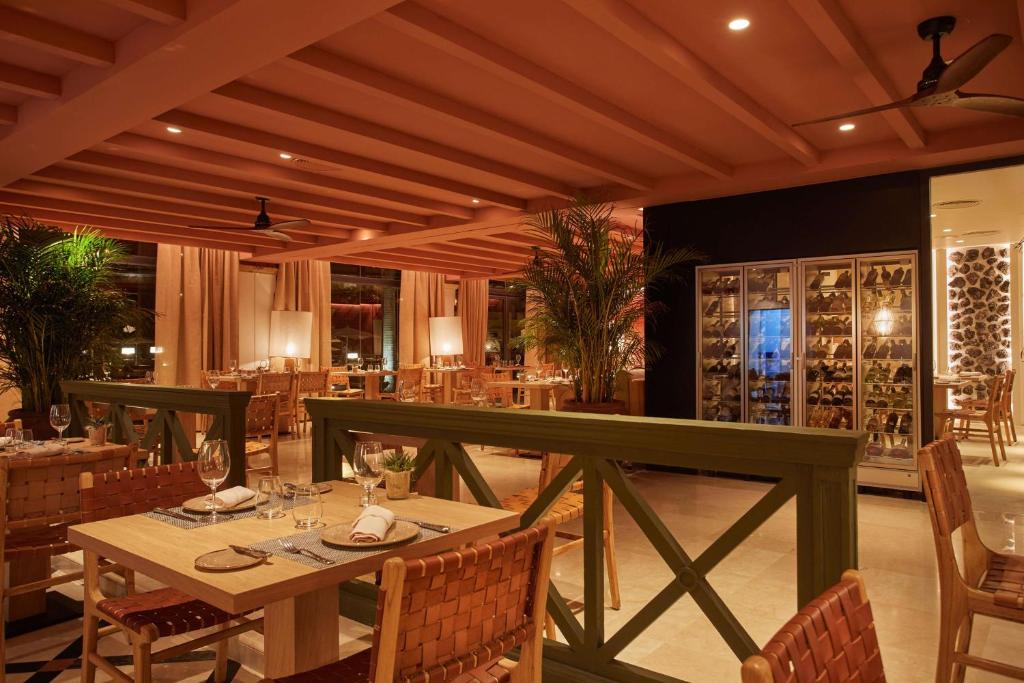 - un restaurant avec une table, des chaises et des bouteilles de vin dans l'établissement Secrets Bahía Real Resort & Spa Adults only, à Corralejo