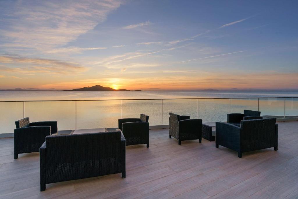 un patio con mesa, sillas y puesta de sol en AluaSun Doblemar, en La Manga del Mar Menor