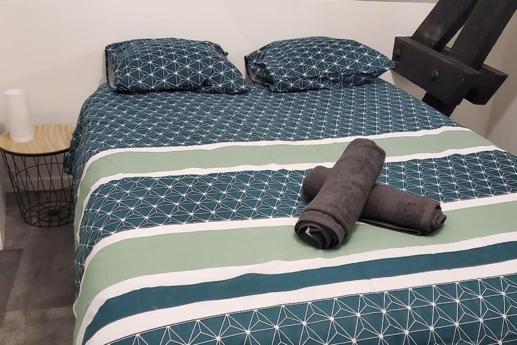 uma cama com dois cobertores e almofadas em Tulsa Home - Comme à la maison em Saint-Quentin