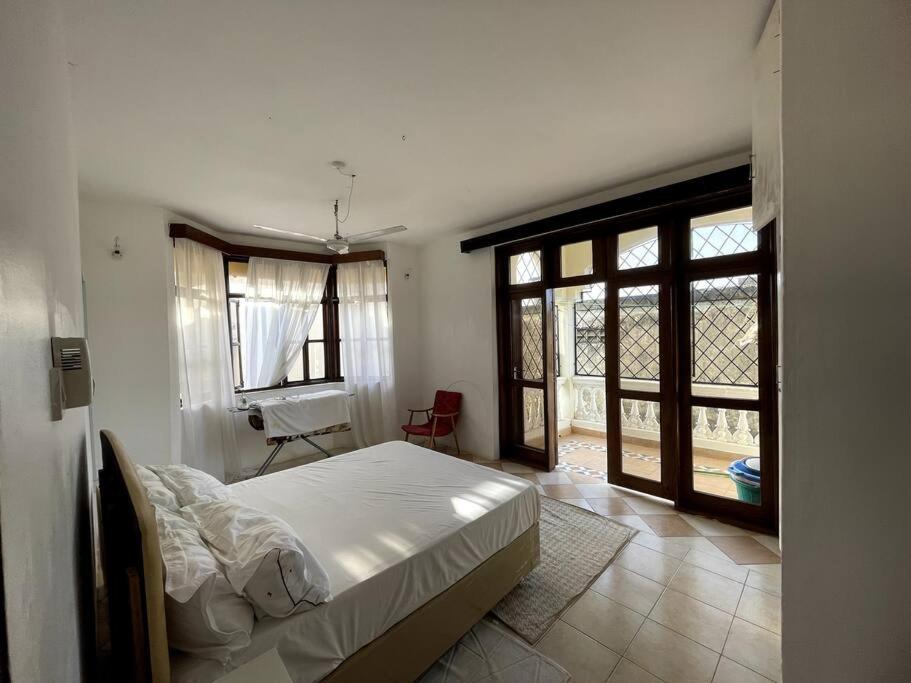 a bedroom with a bed in a room with windows at Mintari Penthouse, Nyali. in Mombasa