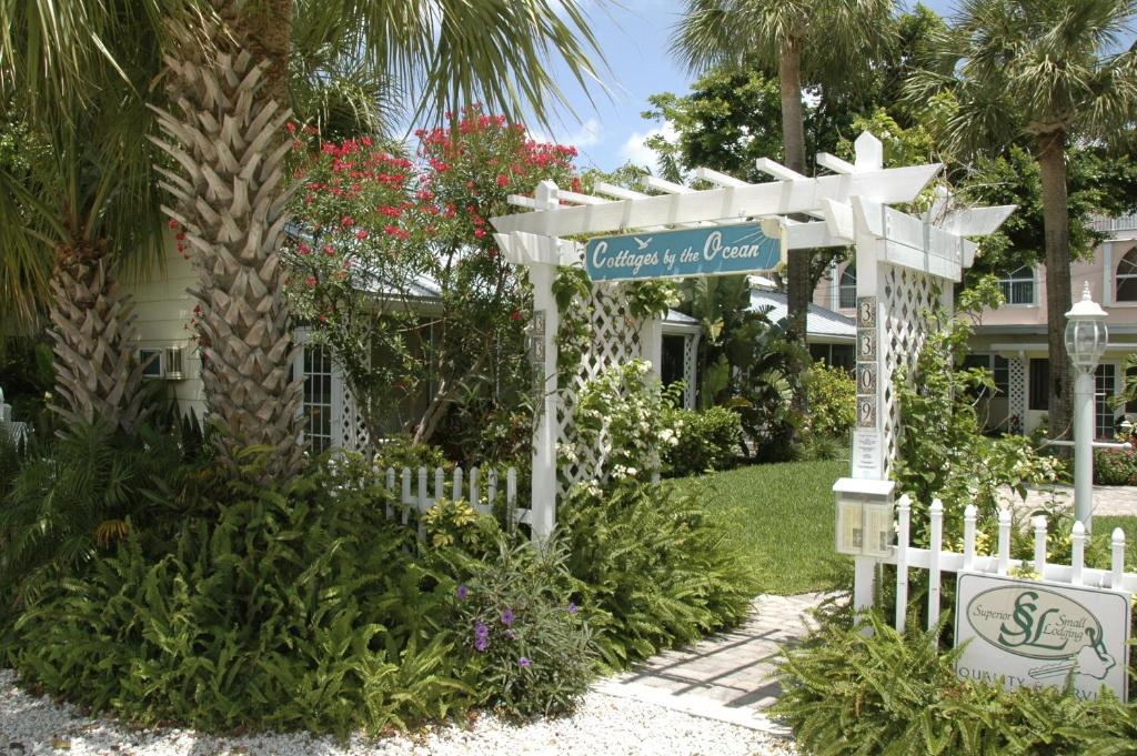 a white fence with a sign in front of a house at Cottages by the Ocean in Pompano Beach