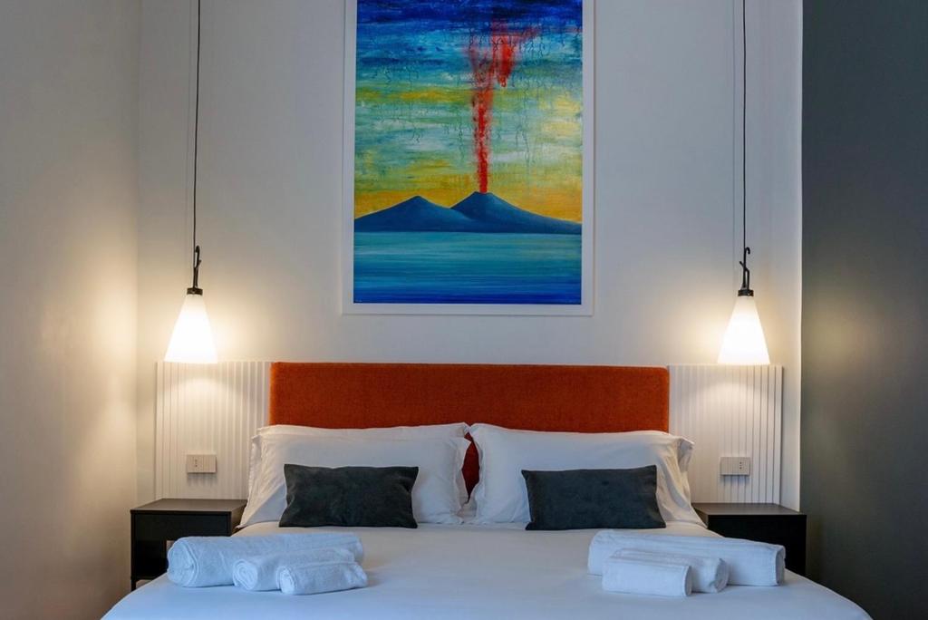 una camera da letto con un letto con due cuscini e un quadro di Rolando Domus a Napoli
