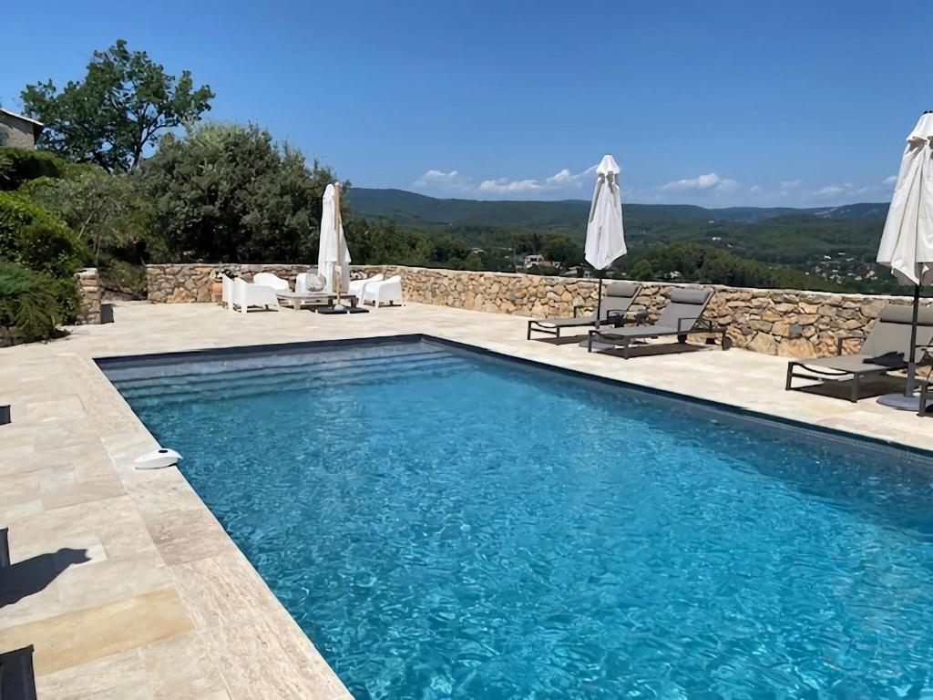 - une piscine avec des chaises et des parasols à côté dans l'établissement Quaint Villa with Private Pool in Flayosc France, à Flayosc