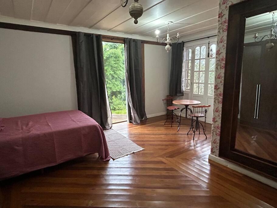 Cette chambre comprend un lit et une table avec des chaises. dans l'établissement Casa Temporada recanto de minas, à Tiradentes
